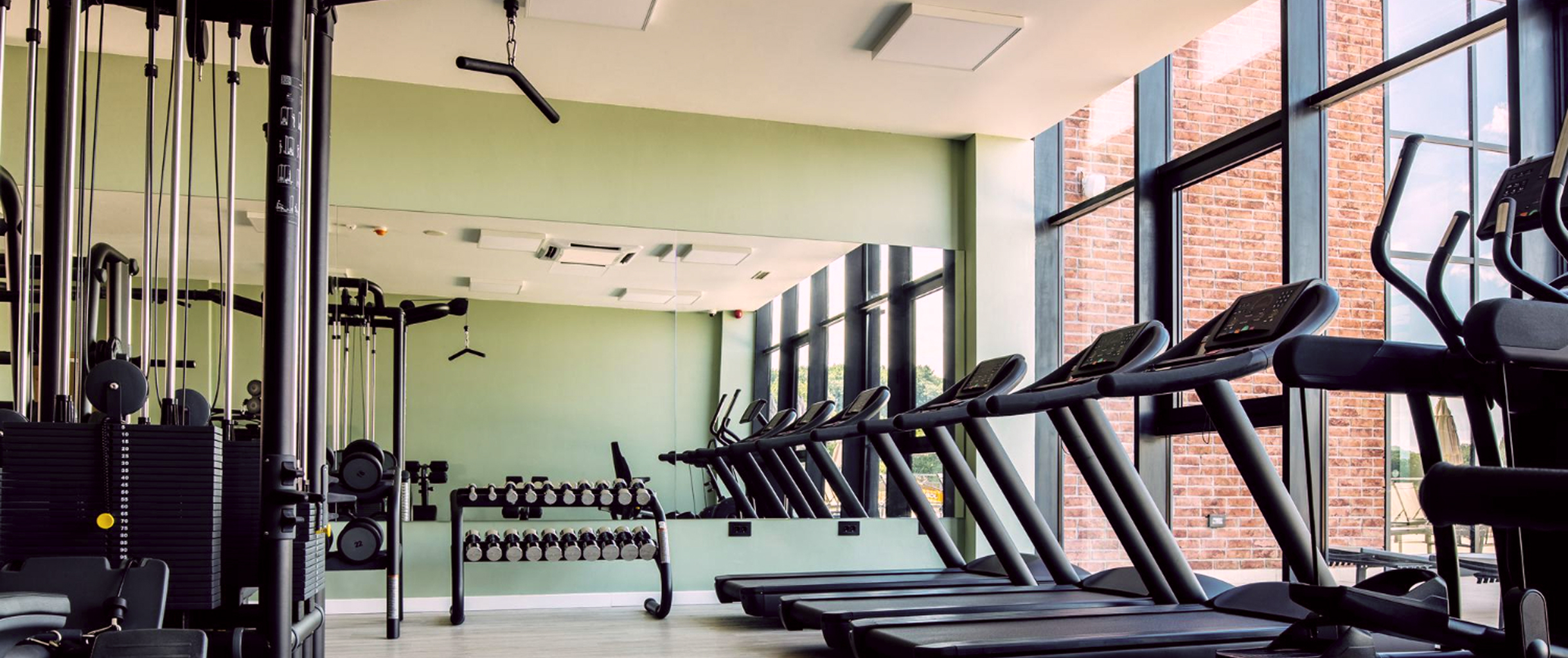 Светлый спорт зал с зеркалом, понарамным окном и большим количетвом спортивного инвентаря 